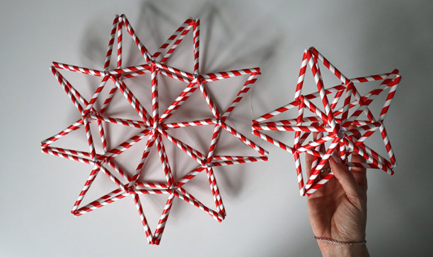 女人的手握着一颗红白相间的星星。旁边还有另一颗星星。白色背景。照片。图片下载