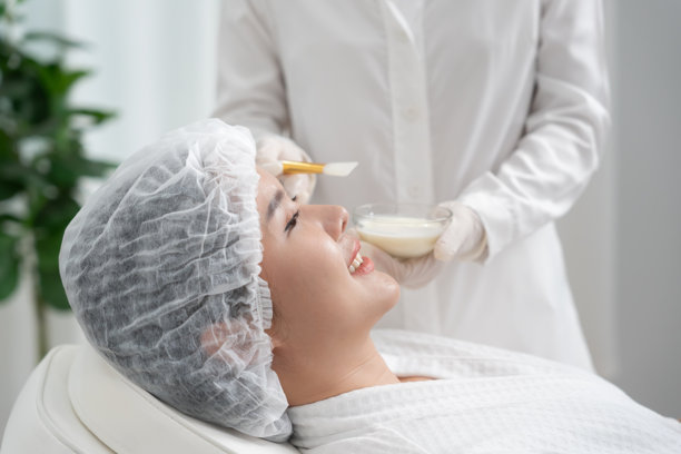 美丽的女性正在接受面部水疗和护理。健康女性的面部涂抹面霜。皮肤霜的广告，抗皱、婴儿般的肌肤、美白、保湿、收缩毛孔精华。图片下载