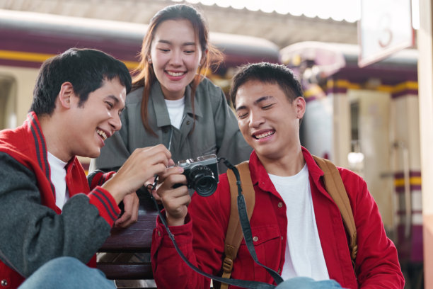 友谊与冒险。一群朋友在火车站兴奋地一起回顾他们的旅行照片。图片下载