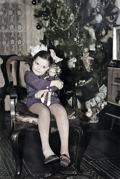 1973年的复古照片，描绘了一位坐在椅子上抱着洋娃娃的小女孩，头上系着蝴蝶结。图片下载