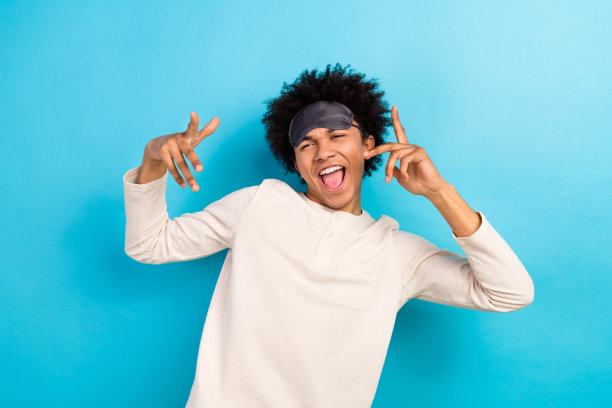 年轻男性在蓝色背景下穿着时尚的白色睡衣，充满活力地跳舞，享受乐趣的照片肖像。图片下载