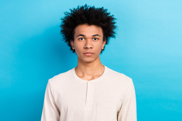 吸引人的年轻男子的照片肖像，穿着时尚的白色睡衣，面对镜头，适合购物横幅，背景为蓝色。图片下载