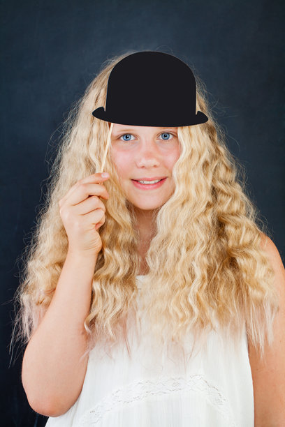快乐的金发孩子在黑色背景下拿着照片亭道具帽子图片下载