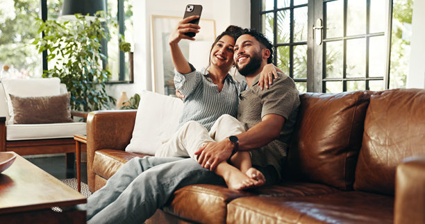 情侣在沙发上自拍，分享爱与微笑，适合社交媒体更新、个人资料照片发布和放松。幸福、亲密和摄影，男人和女人在家中客厅中建立联系。图片下载
