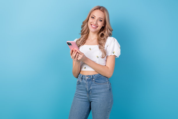 年轻有趣的女友在蓝色背景下使用苹果手机发短信聊天的照片肖像图片下载