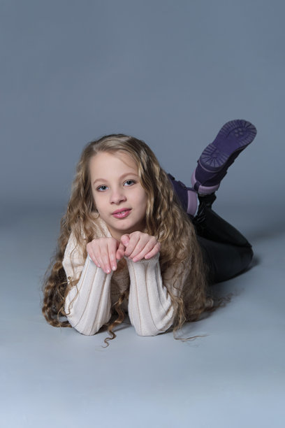 年轻女孩放松地躺着，做出两个和平手势，脸上带着满足的表情。这张图片展现了青春的魅力和快乐的本质，强调无忧无虑的时刻和自我表达。图片下载