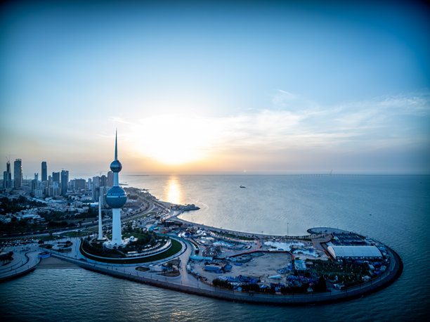 一张夕阳下阿拉伯海湾街沿岸塔楼的航拍照片，展示了科威特市塔楼的建筑工程奇迹。图片下载