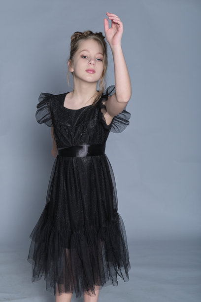 一位穿着黑色荷叶边裙子的年轻舞者优雅地伸展手臂，展现出优雅与灵动。这张图片展示了儿童舞蹈的美，融合了舞动与高端时尚，呈现出一种精致的外观。图片下载