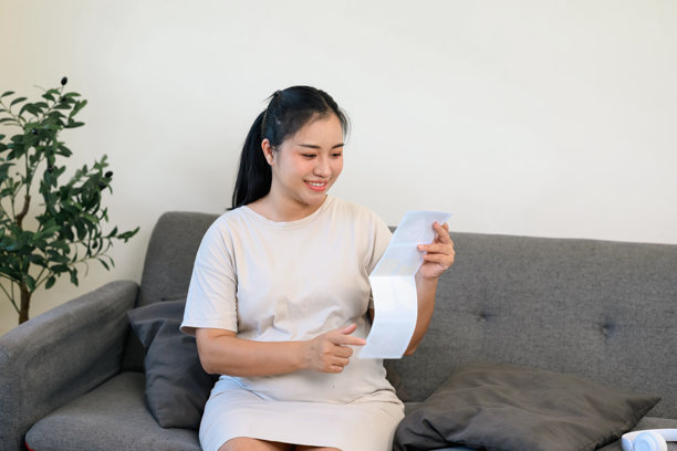 孕妇欣赏超声波照片，轻轻抚摸她的肚子图片下载