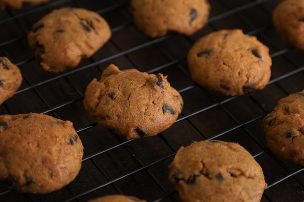 黑色冷却架上整齐排列的巧克力曲奇饼干，放在木桌上，留有空白空间。平视照片。图片下载