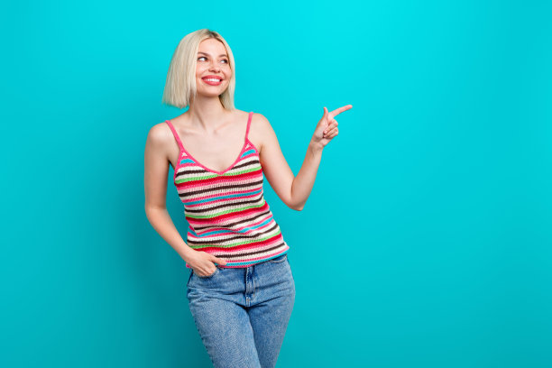 时尚条纹服装的可爱年轻女士在水绿色背景下指向空白处的照片肖像图片下载
