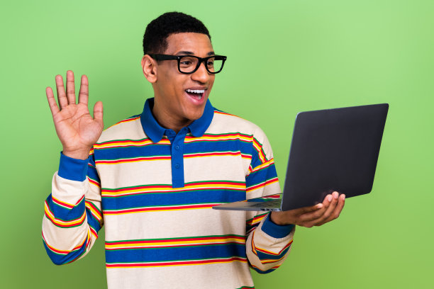 年轻男性视频通话的照片肖像，挥手打招呼，穿着时尚的条纹服装，背景为绿色。图片下载