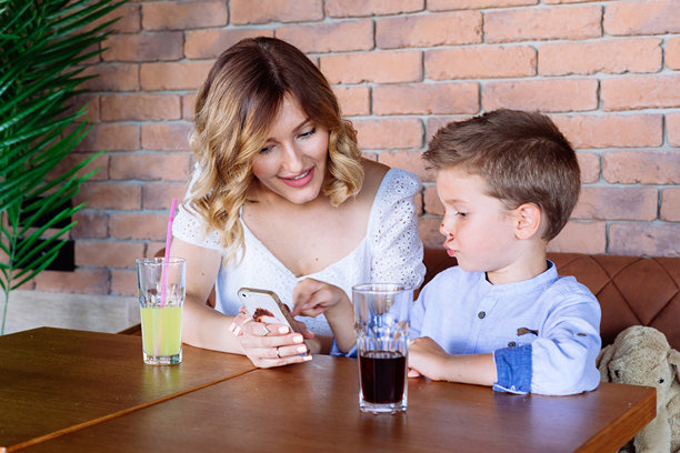 妈妈和她的儿子在看手机。她正在给他展示一些照片。图片下载