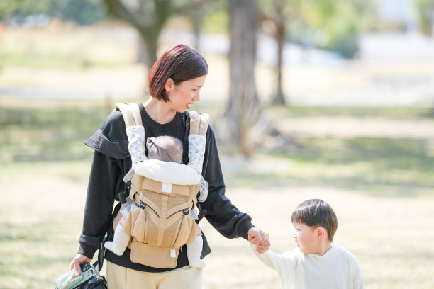 在福冈的公园里，春天，一位三十多岁的妈妈与她三岁的儿子和六个月大的女婴一起慢慢散步。这张照片展现了一个宁静而祥和的家庭户外时刻。图片下载