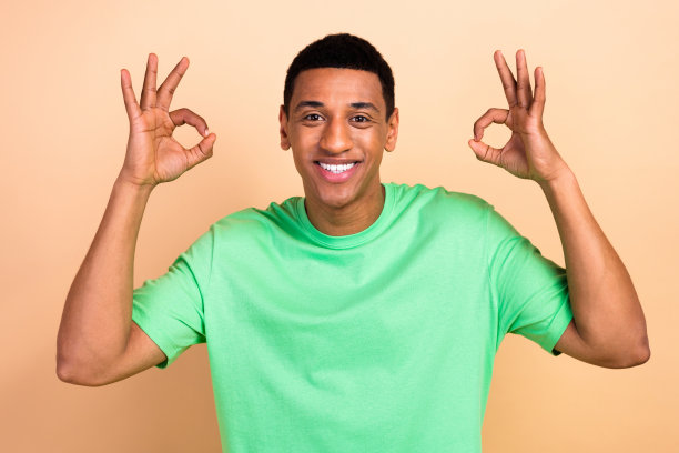 穿着时尚绿色衣服的迷人年轻男子在米色背景下展示双手OK手势的照片肖像图片下载