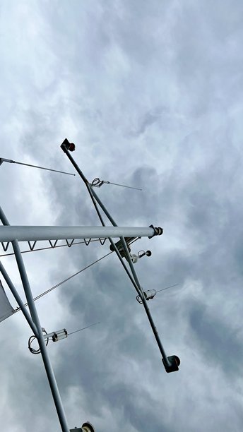 一张垂直照片，展示了一艘游艇的桅杆与戏剧性的灰色天空相映衬。图片下载