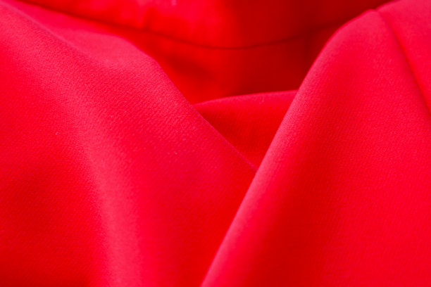鲜艳红色的布料特写，柔和的褶皱和细腻的纹理。这张图片非常适合用于背景制作、展示材料或与时尚和设计相关的项目。图片下载