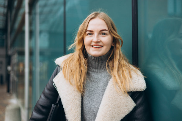 时尚迷人的年轻女性微笑着走在现代街道上，穿着冬季服装。城市生活方式概念。户外快乐女性的肖像，面向镜头。高质量照片。图片下载