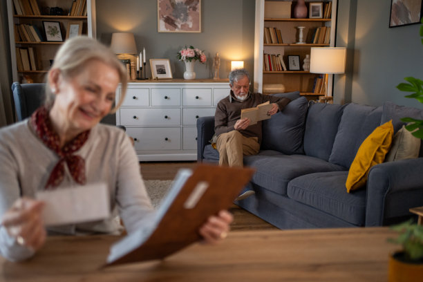 老年夫妇在家放松：他在看书，她在微笑着看旧照片图片下载