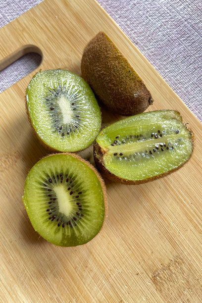 竹板上的猕猴桃。多汁的水果，鲜艳的绿色果肉。适合健康饮食、水果和素食主义的主题。图片下载