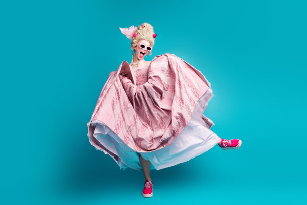 年轻贵族女性穿着巴洛克风格的裙子，脚踩时尚鞋子，独自在青绿色背景下跳舞的全身照片图片下载