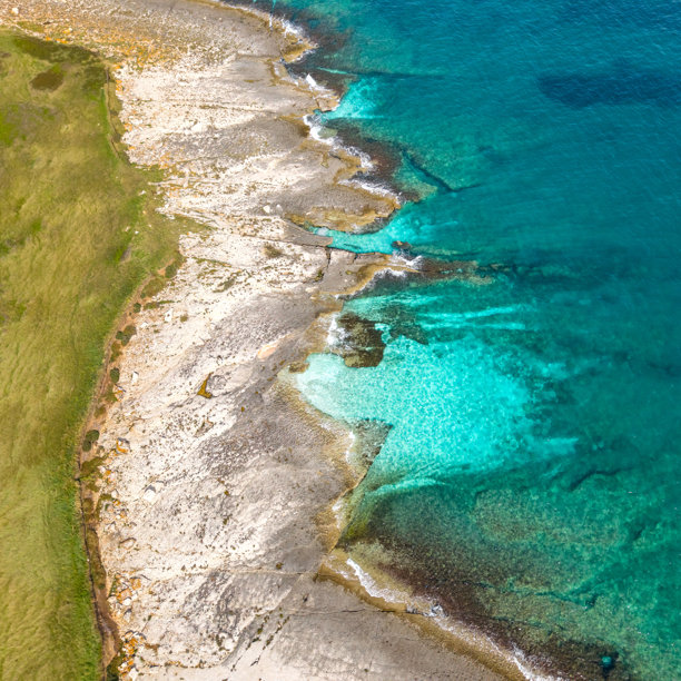 俯视照片捕捉了从草地到明亮石灰岩和浅显清澈水域的过渡。图片下载