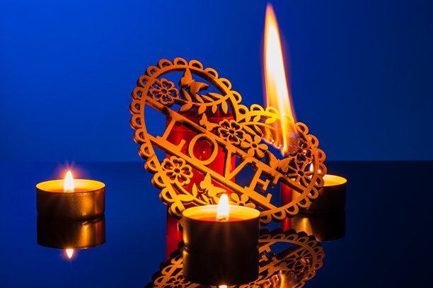 浪漫的蜡烛在照片中闪烁，环绕着一个装饰性的木制心形物件图片下载