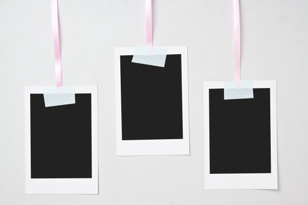 三张空白的宝丽来相纸用胶带挂在绳子上，背景为白色。样板、模板或留白。即时相机照片打印框架图片下载