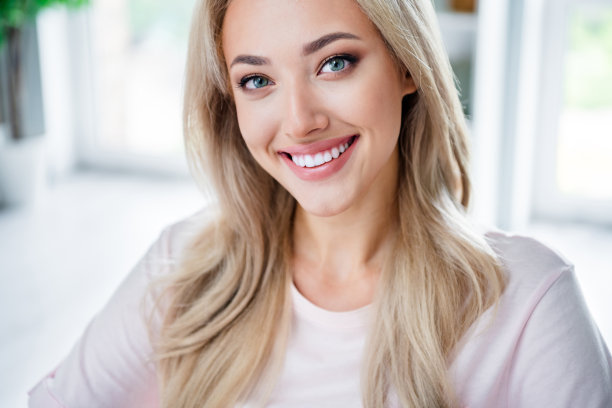 可爱的年轻女性微笑着的照片肖像，迷人的员工在现代家居设计的工作室中，穿着白色T恤。图片下载