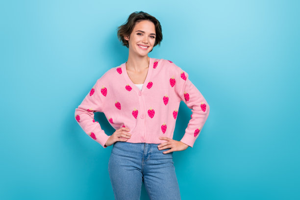 穿着粉色图案衣服的满意女士在蓝色背景上展示新系列的照片图片下载