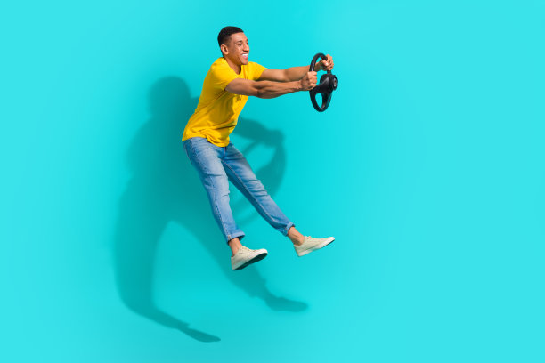 穿着黄色T恤的搞笑酷男士在青色背景下高高跳起的全身照片图片下载