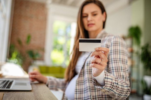 年轻的孕妇在明亮现代的地方使用支付卡进行在线购物图片下载