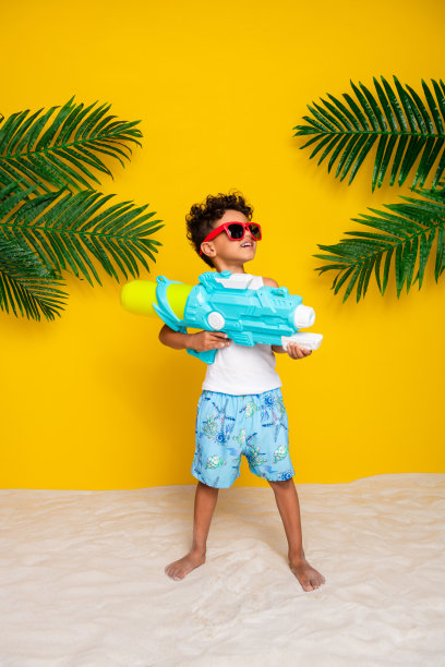 全身竖版照片，搞笑可爱的小男孩穿着白衬衫，戴着深色眼镜，正在水中升起，背景为黄色。图片下载