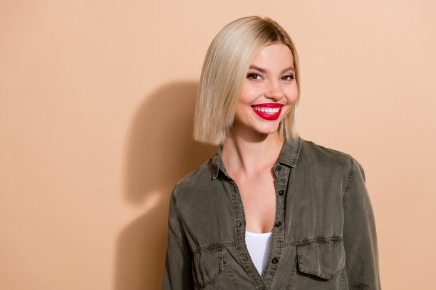 特写照片，吸引人的模特女士，红色丰满的嘴唇，白色的牙齿，穿着卡其色衬衫，背景为米色。图片下载