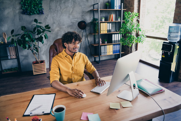年轻帅气的男子穿着黄色衬衫，在现代家居设计的工作室中远程办公的照片肖像图片下载