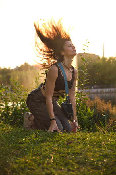 一位女性沐浴在温暖的晚霞中，跪在宁静的湖边，神情真诚而开放。这张照片捕捉了真实的本质和拥抱脆弱之美。图片下载