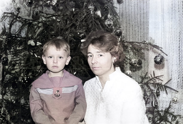 复古的肖像，描绘一个小男孩和他的母亲在圣诞树旁。1970年的老照片。图片下载