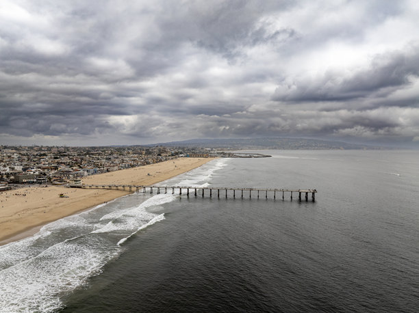 赫莫萨海滩码头的航拍照片，背景是阴郁的云层和帕洛斯维德斯。图片下载