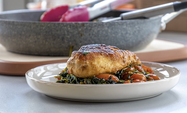 美味的熟鸡胸肉与菠菜和樱桃番茄的特写照片。干净、均衡、健康的晚餐。图片下载