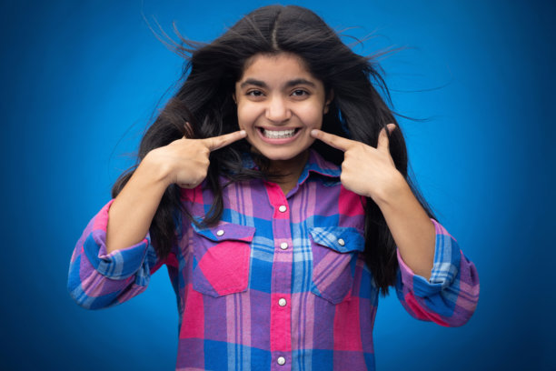 迷人可爱的年轻女孩，直发，独自站在蓝色背景前的肖像照片图片下载