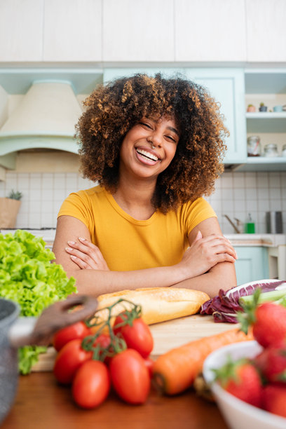 快乐的年轻黑人女性在家厨房里微笑着做沙拉，使用新鲜蔬菜 - 肖像照片 - 食物与生活方式概念图片下载