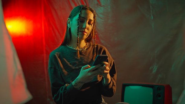 女人在背景中查看智能手机，旁边有一台复古电视图片下载