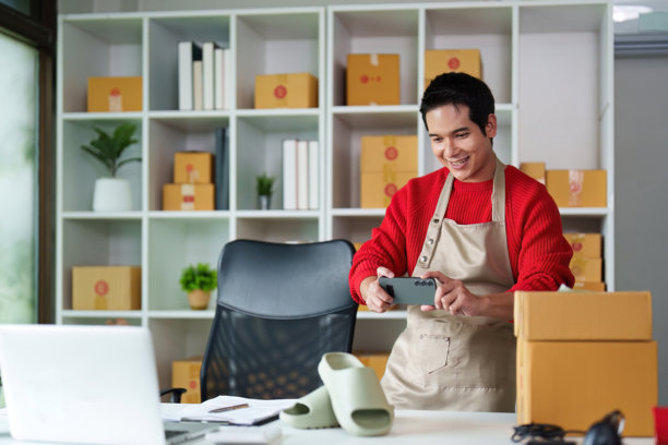 小型企业与电子商务。一位企业家在井然有序的工作空间中拍摄产品照片。图片下载