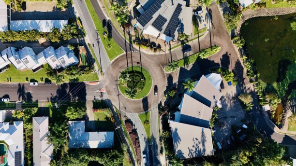 昆士兰州凯恩斯的三位一体海滩 – 海岸环形交叉口、热带树木、住宅区、道路网络和北昆士兰郁郁葱葱的郊区风景的航拍照片图片下载