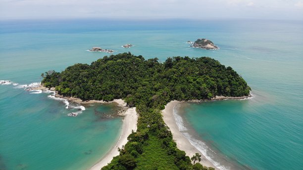 令人印象深刻的从上往下拍摄的无人机航拍照片，展示了哥斯达黎加国家公园内偏远的曼努埃尔安东尼奥海滩。空旷对称的沙洲，深绿色的棕榈树指向小热带岛屿。中美洲的自然风光。自然的完美。图片下载