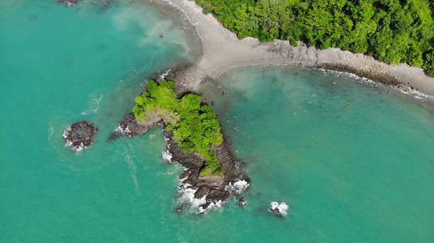 令人印象深刻的从上往下拍摄的无人机航拍照片，展示了哥斯达黎加马努埃尔安东尼奥国家公园内一处偏远海滩。空旷的对称帽子，周围环绕着小热带岛屿和深绿色的丛林环境。中美洲自然风光。图片下载