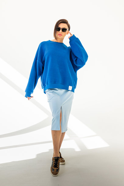 穿着蓝色卫衣和浅蓝色裙子的优雅女性，背景为白色。时尚女性风格。工作室摄影。竖版照片。图片下载