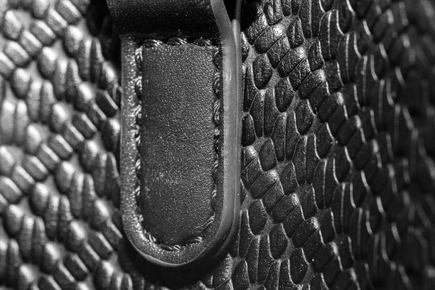 黑色皮革纹理的特写照片。缝合线展示了黑色皮革包的针脚。图片下载