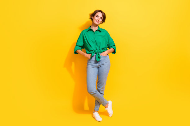 穿着绿色衬衫的阳光女孩在黄色背景下微笑着走路的全身照片图片下载