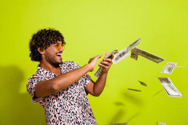 年轻男性穿着时尚的粉色豹纹服装，愉快地在黄色背景下挥霍金钱的肖像照片图片下载